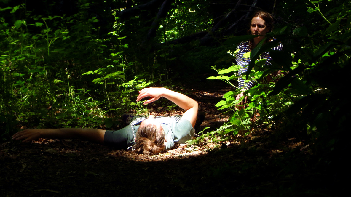 woman lying in a sun pool in the forest with an onlooking witness